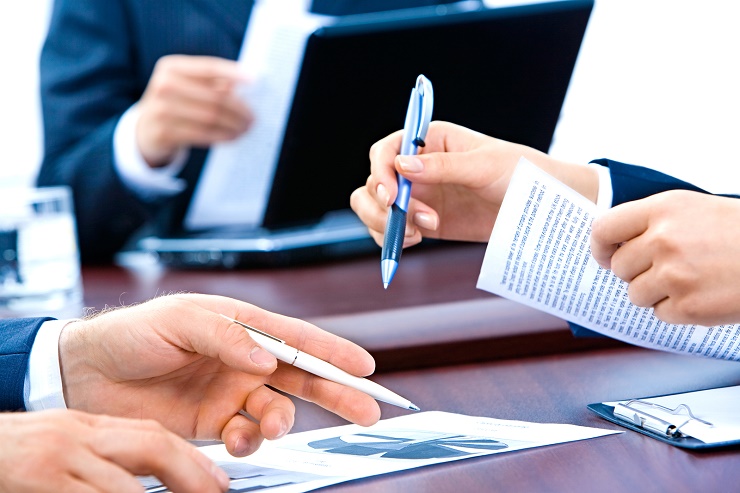 Close-up of business peoples hands holding pens and documents at meeting